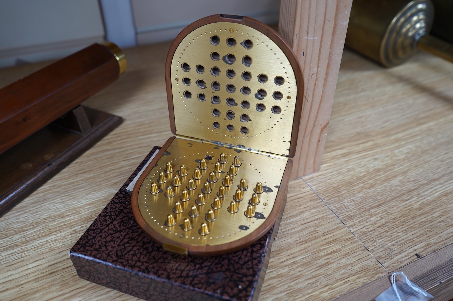 A reproduction 19th century style wooden bodied kaleidoscope on stand, 29.5cm, together with a wood cased brass solitaire set (one peg missing), 10.5cm diameter. Condition - fair.